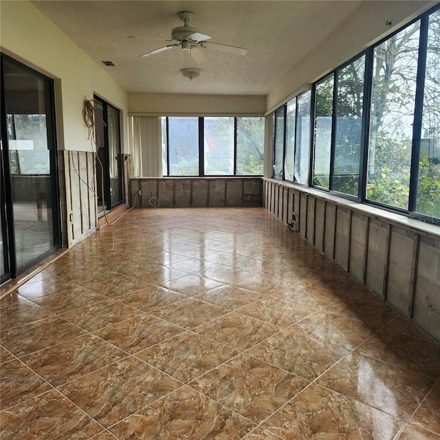 unfurnished sunroom with visible vents and a ceiling fan