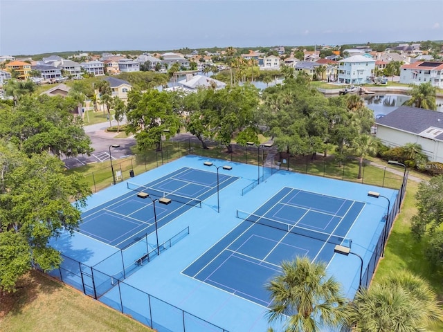 view of sport court featuring a water view, a residential view, and fence