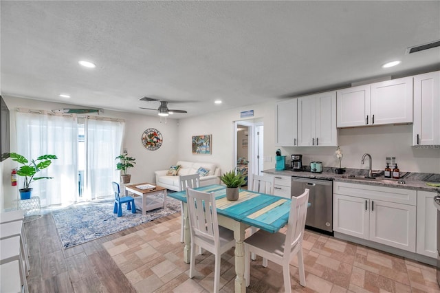 kitchen with white cabinetry, sink, light stone counters, and stainless steel dishwasher