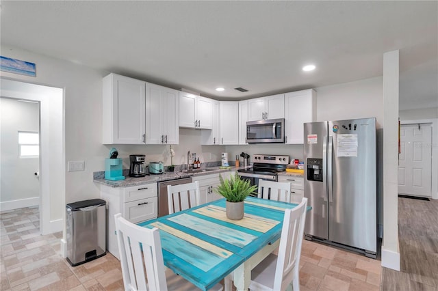 kitchen featuring sink, stainless steel appliances, white cabinets, and light stone countertops