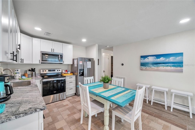 kitchen featuring light stone counters, sink, white cabinets, and appliances with stainless steel finishes