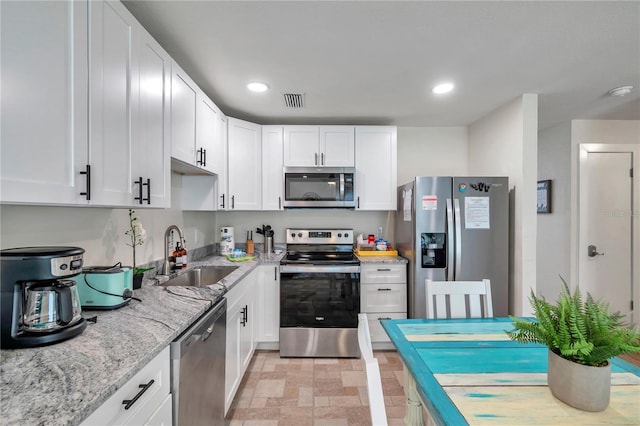 kitchen featuring light stone counters, sink, white cabinets, and appliances with stainless steel finishes