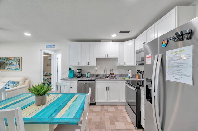 kitchen featuring white cabinetry, sink, light stone countertops, and appliances with stainless steel finishes