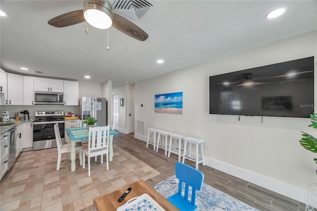 kitchen with stainless steel appliances, white cabinetry, ceiling fan, and light hardwood / wood-style floors