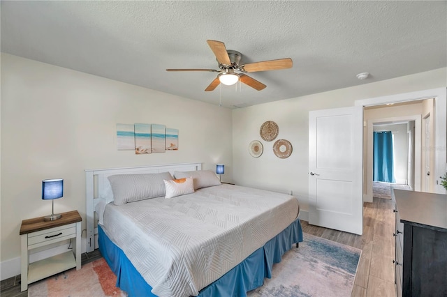 bedroom with hardwood / wood-style floors, a textured ceiling, and ceiling fan