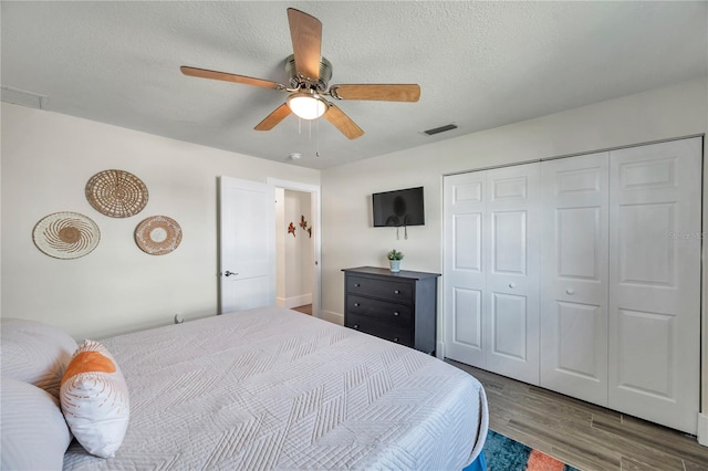 bedroom featuring ceiling fan, a closet, wood-type flooring, and a textured ceiling