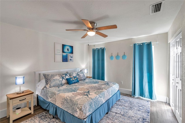 bedroom with hardwood / wood-style floors, a textured ceiling, and ceiling fan