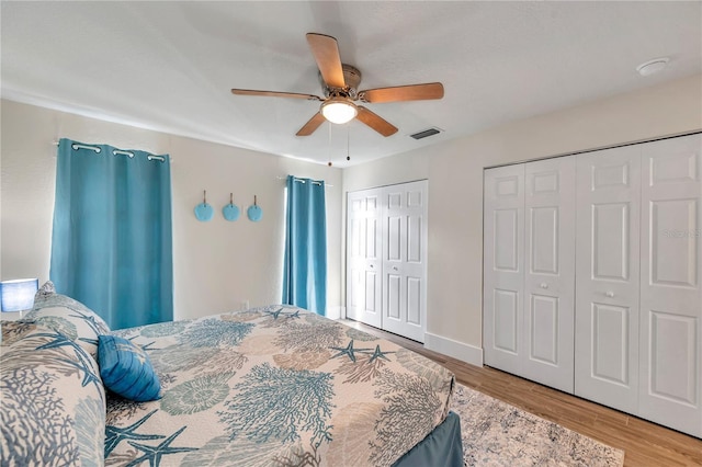 bedroom featuring multiple closets, ceiling fan, and hardwood / wood-style floors