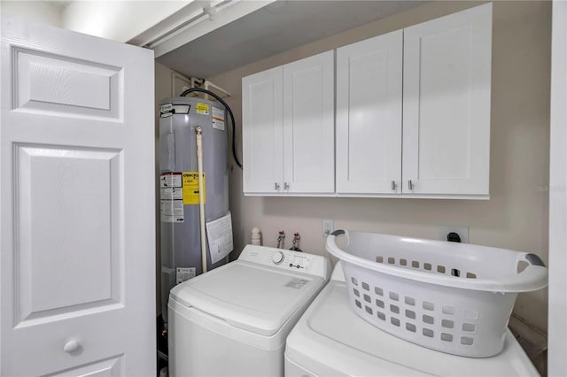 washroom with cabinets, washer and clothes dryer, and electric water heater