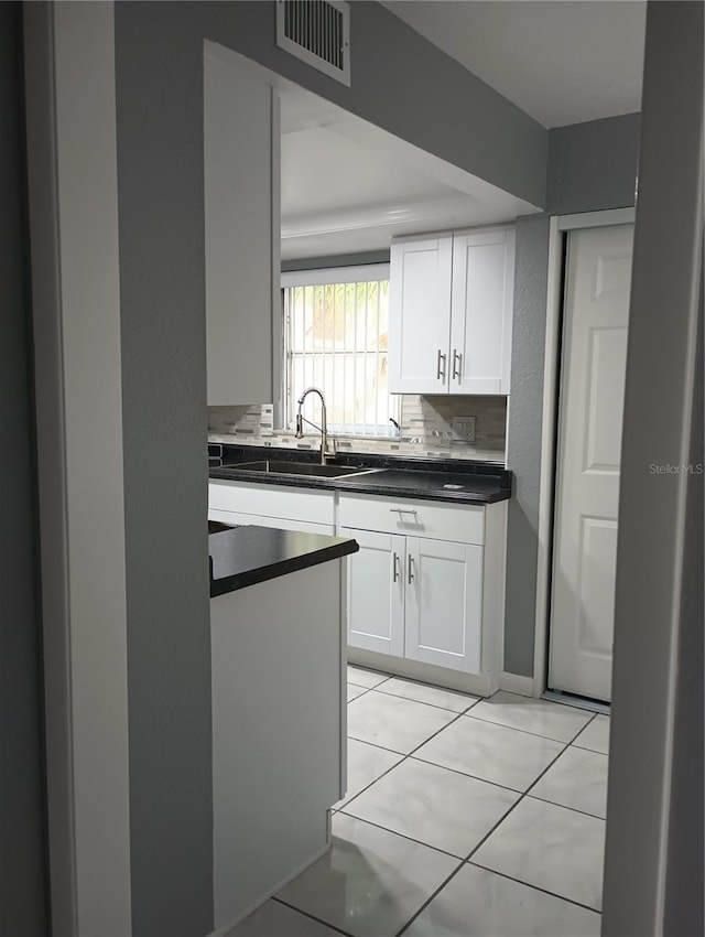 kitchen featuring light tile patterned floors, sink, decorative backsplash, and white cabinets