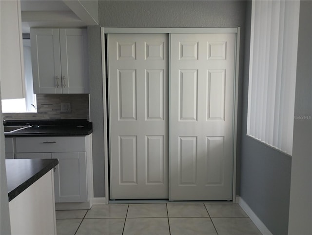 kitchen featuring light tile patterned floors, white cabinets, and backsplash