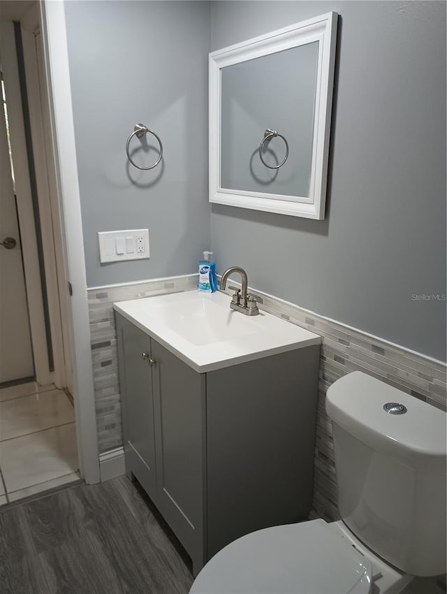 bathroom featuring tile walls, vanity, hardwood / wood-style floors, and toilet