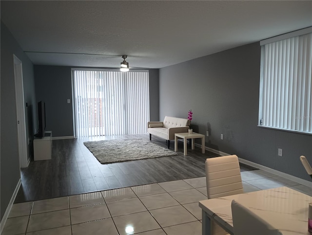 living room with light tile patterned floors, a textured ceiling, and ceiling fan