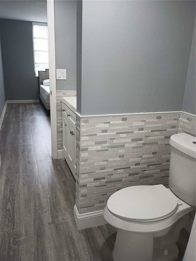 bathroom with vanity, wood-type flooring, tile walls, and toilet