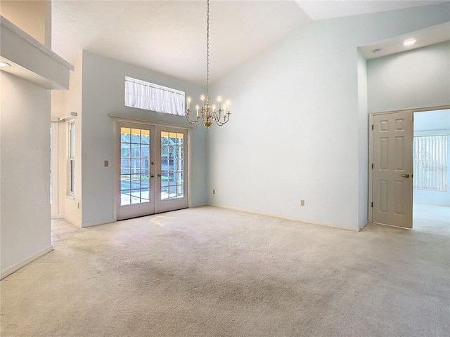 carpeted spare room featuring high vaulted ceiling, french doors, and a chandelier