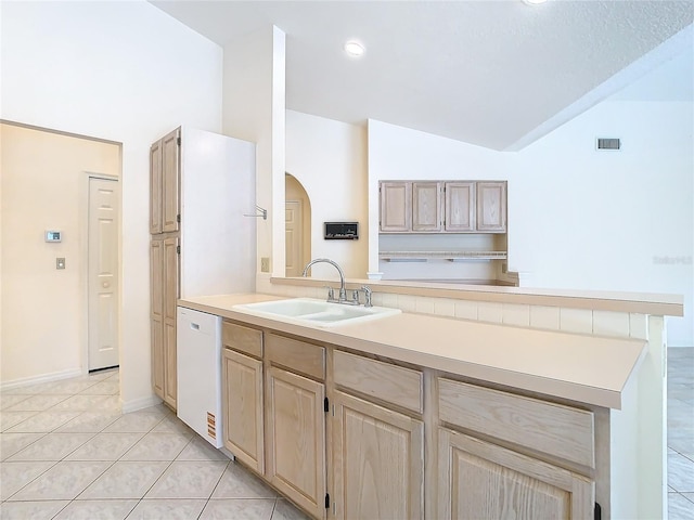 kitchen featuring lofted ceiling, light brown cabinetry, sink, light tile patterned floors, and white dishwasher