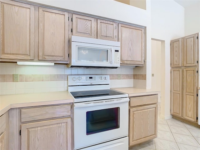 kitchen with backsplash, light brown cabinetry, white appliances, and light tile patterned floors