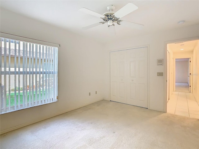 unfurnished bedroom featuring light colored carpet, ceiling fan, and a closet