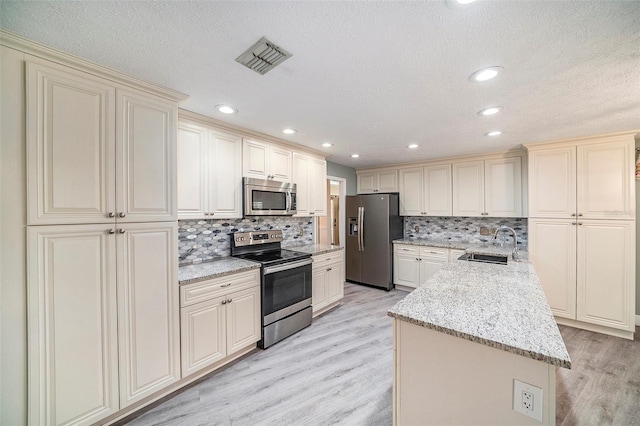 3013 Ridgevale Cir, Valrico, FL 33596 - kitchen featuring visible vents, a sink, cream cabinetry, light wood finished floors, and stainless steel appliances