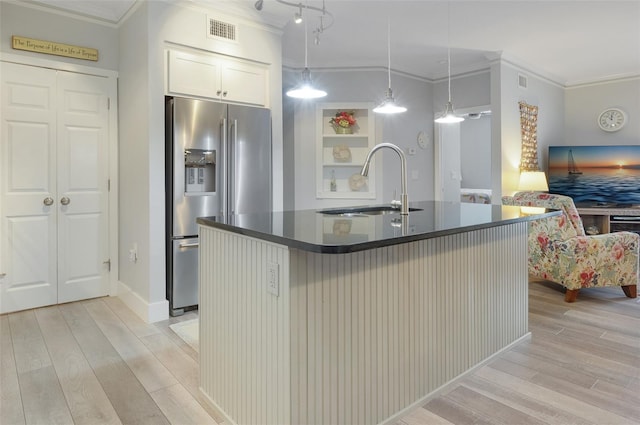 kitchen featuring dark countertops, pendant lighting, a kitchen island with sink, and stainless steel refrigerator with ice dispenser