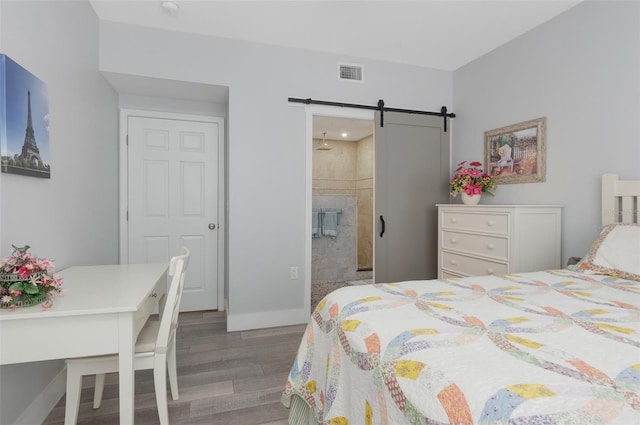 bedroom featuring light wood-type flooring, a barn door, visible vents, and baseboards