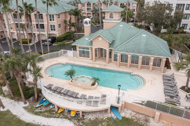 view of pool with a patio area, fence, and a pool with connected hot tub