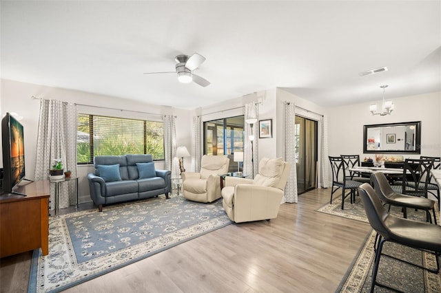 living room with visible vents, wood finished floors, and ceiling fan with notable chandelier