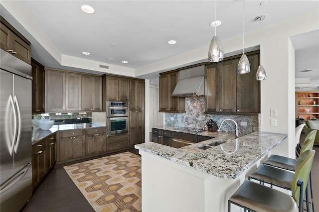 450 Knights Run Ave Unit 1704, Tampa, FL 33602 - kitchen featuring appliances with stainless steel finishes, wall chimney exhaust hood, backsplash, a peninsula, and dark brown cabinetry