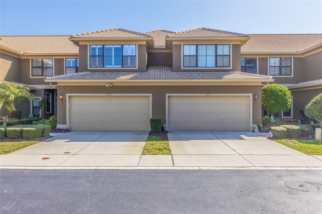 multi unit property featuring a tiled roof, an attached garage, and stucco siding