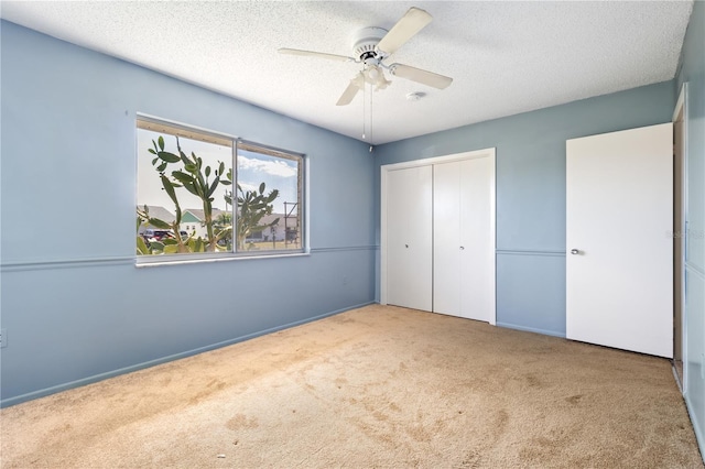 unfurnished bedroom with a closet, a textured ceiling, a ceiling fan, and carpet floors