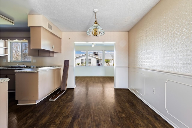 kitchen featuring visible vents, a textured ceiling, dark wood finished floors, and wainscoting