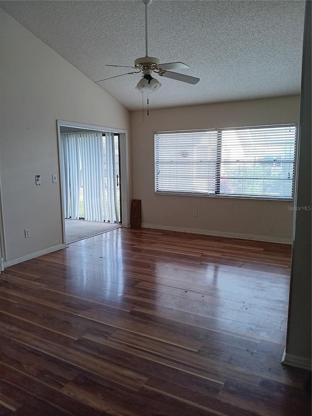 spare room with vaulted ceiling, plenty of natural light, a textured ceiling, and dark hardwood / wood-style flooring