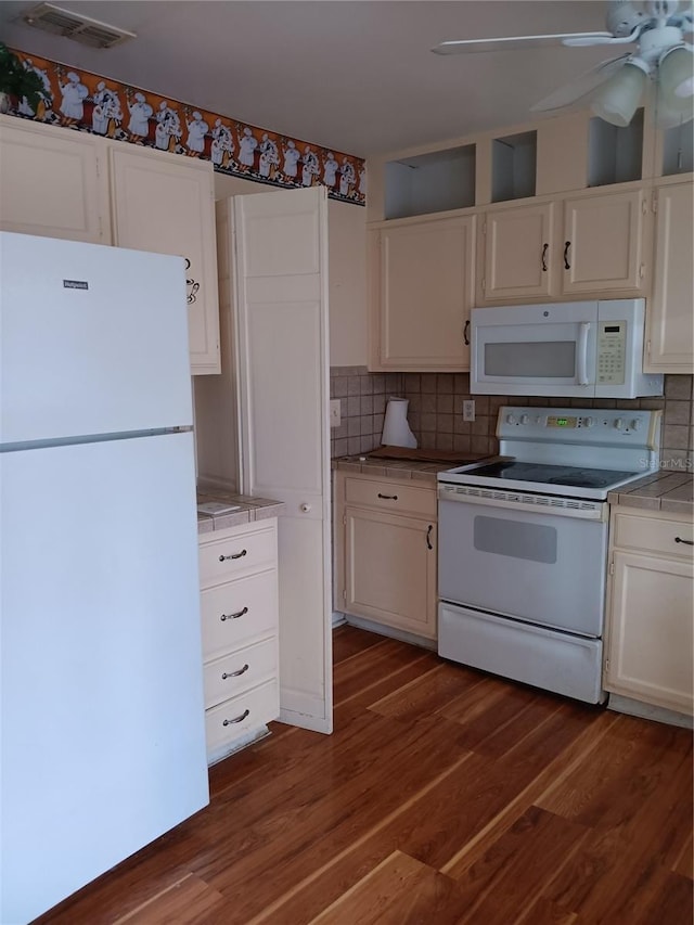 kitchen featuring dark hardwood / wood-style flooring, backsplash, white appliances, and white cabinets