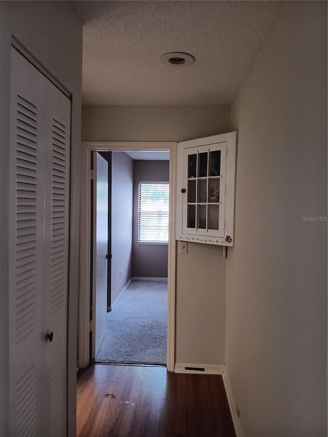 corridor with hardwood / wood-style floors and a textured ceiling