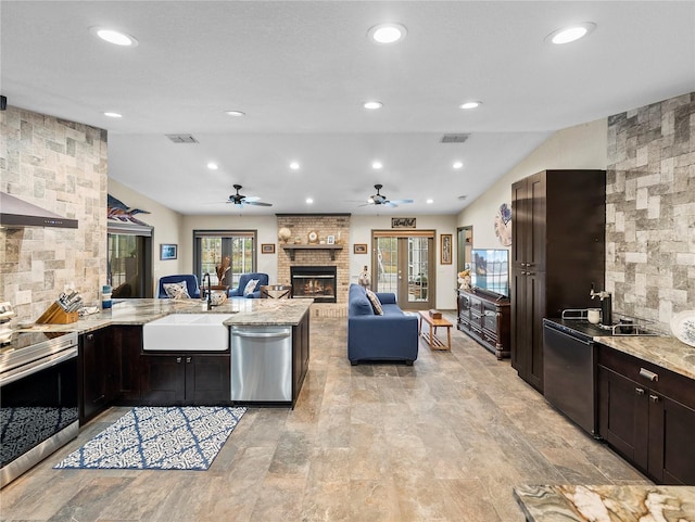 kitchen with a brick fireplace, sink, light stone counters, stove, and dishwasher