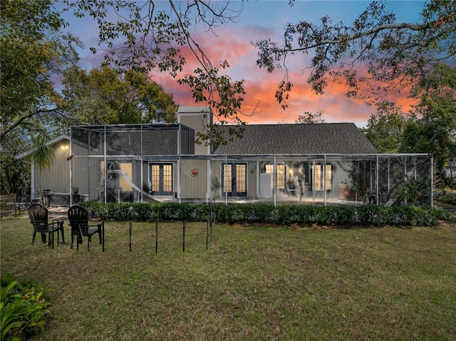 back house at dusk featuring a yard and a patio area