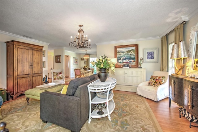 living room with a textured ceiling, crown molding, a chandelier, and light hardwood / wood-style floors