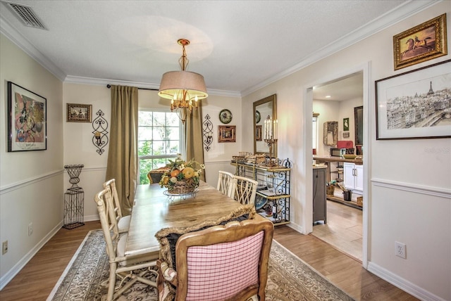 dining area featuring an inviting chandelier, light hardwood / wood-style flooring, and ornamental molding