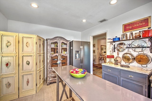 kitchen with gray cabinets, light hardwood / wood-style flooring, light stone counters, and stainless steel refrigerator with ice dispenser