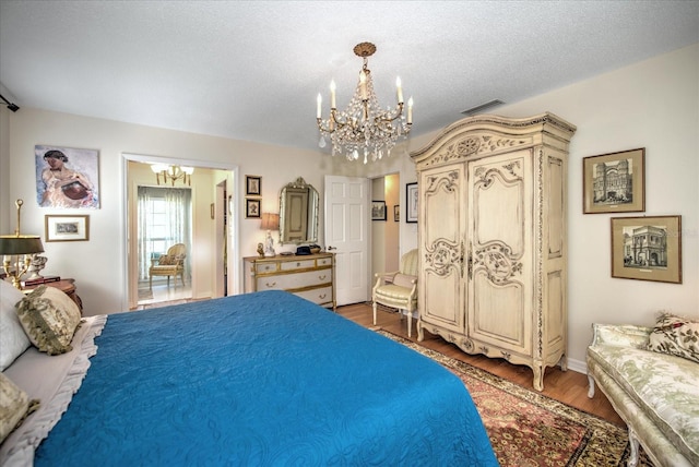 bedroom featuring a textured ceiling, dark hardwood / wood-style floors, and a notable chandelier