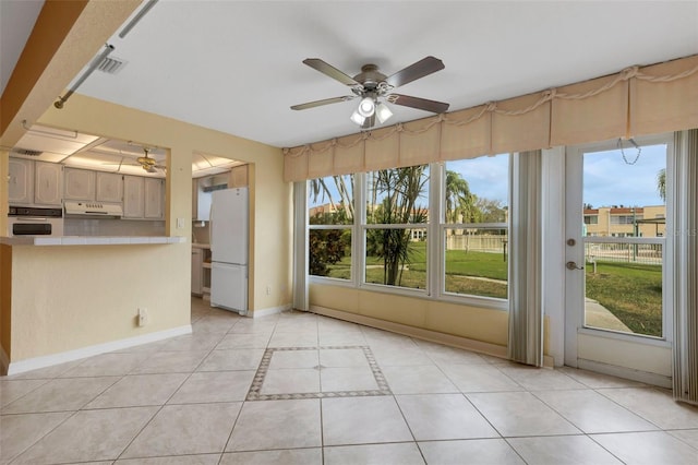 unfurnished living room featuring light tile patterned floors, plenty of natural light, a ceiling fan, and baseboards