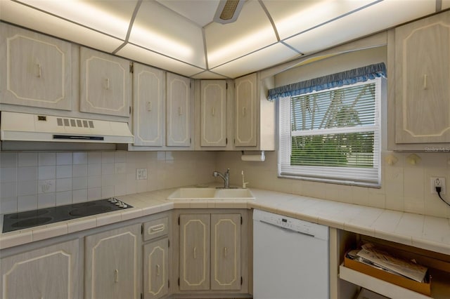 kitchen featuring a sink, under cabinet range hood, tile counters, and dishwasher