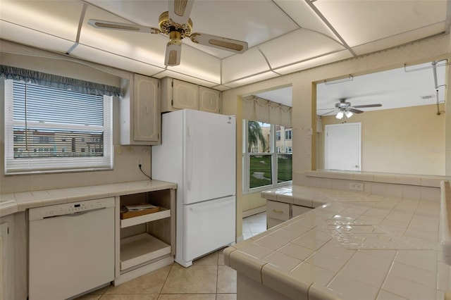 kitchen with white appliances, light tile patterned flooring, ceiling fan, and tile countertops