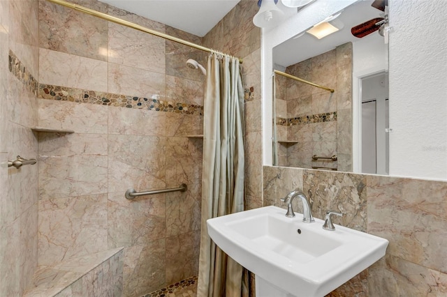 full bathroom with a stall shower, tasteful backsplash, tile walls, and a sink