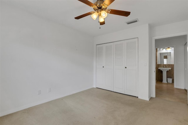 unfurnished bedroom featuring a closet, light colored carpet, visible vents, a sink, and baseboards