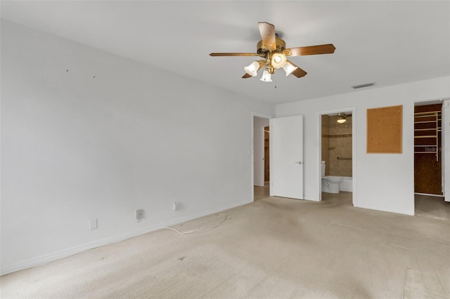 unfurnished bedroom with a spacious closet, visible vents, connected bathroom, and light colored carpet