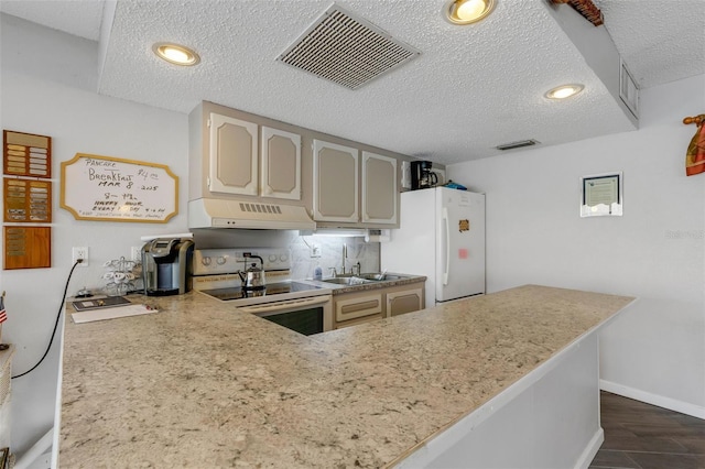 kitchen with visible vents, light countertops, a textured ceiling, white appliances, and under cabinet range hood