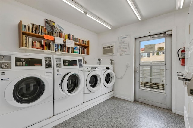 common laundry area with a wall mounted AC, washing machine and dryer, and baseboards