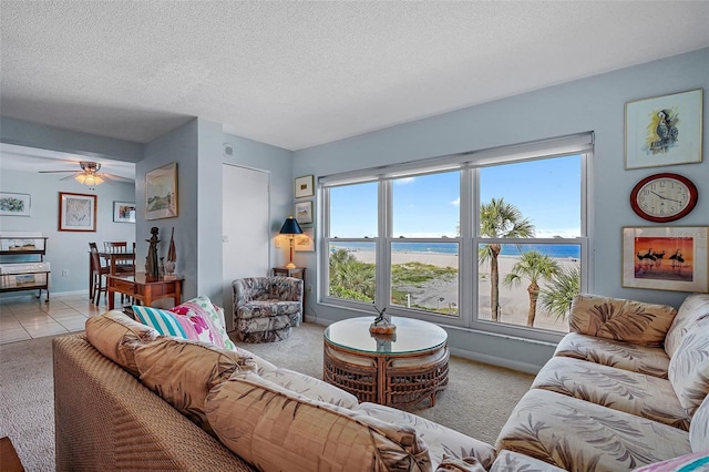 living room with light tile patterned floors, ceiling fan, a textured ceiling, and a water view