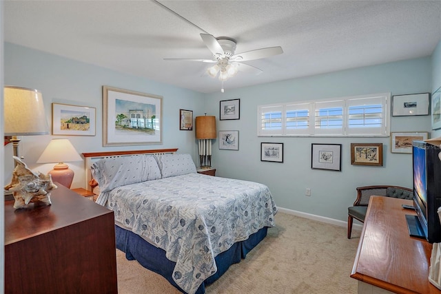 bedroom with ceiling fan, light colored carpet, and a textured ceiling